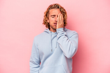 Young caucasian man isolated on pink background tired and very sleepy keeping hand on head.