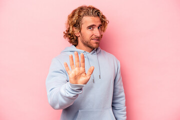 Young caucasian man isolated on pink background rejecting someone showing a gesture of disgust.