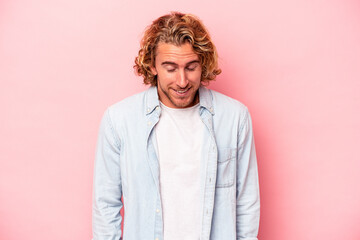 Young caucasian man isolated on pink background laughs and closes eyes, feels relaxed and happy.