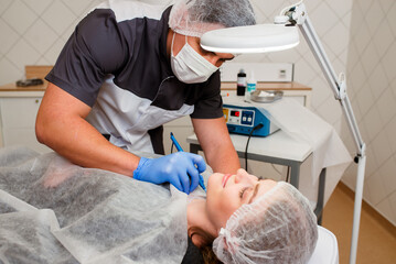 Professinal beautician surgeon using a laser device for removing mole. Removal of birthmark from...