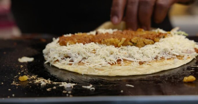 A Chef making Vegetable Frankie, Kathi Roll, Veg Franky Wrap. Adding Sauces, Potato Filling, spices to Cabbage Salad on a Indian Refined Flour Flat bread. Mumbai, Maharashtra, India. 4811.