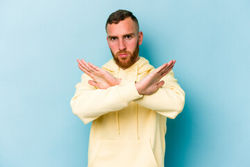Young caucasian man isolated on blue background doing a denial gesture