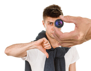 Young confident man showing dislike on white background, male hand holding mini video camera in the...