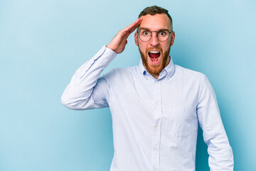 Young caucasian man isolated on blue background shouts loud, keeps eyes opened and hands tense.