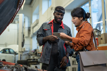 Waist up portrait of female client giving digital signature via tablet at car repair shop, copy space