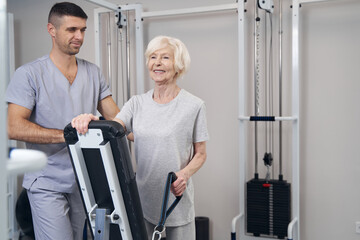 Pensioner holding cable pulley weight machine handle in hand