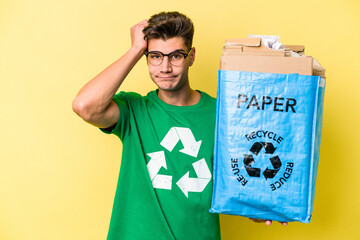 Young caucasian man holding a recycling bag full of paper to recycle isolated on yellow background being shocked, she has remembered important meeting.