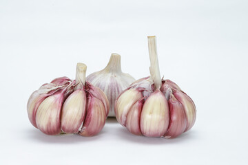 Three heads of garlic (Allium sativum), with their units still in the bulb, one with the peel and two without, on a neutral background