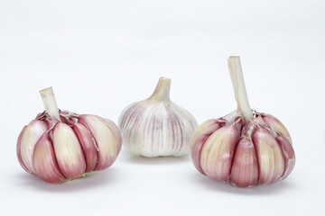 Three heads of garlic (Allium sativum), with their units still in the bulb, one with the peel and...