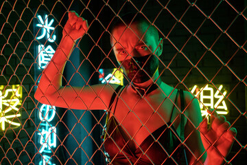 Cyberpunk girl with leather tank top standing behind the bars with neon hieroglyphs meaning nirvana...