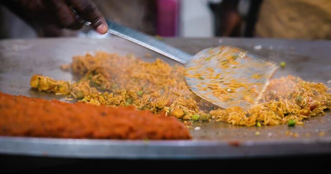 A chef preparing a popular Indian fast food Rice dish Tawa Pulao, Pulav, Biryani, Fried Rice in a hot pan. It is a mix of fresh vegetables, spices and rice. Juhu beach, Mumbai, Maharashtra, India 4804