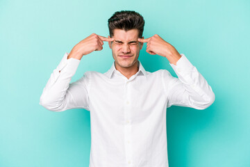 Naklejka premium Young caucasian man isolated on blue background focused on a task, keeping forefingers pointing head.