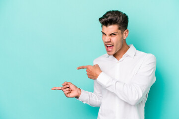 Young caucasian man isolated on blue background pointing with forefingers to a copy space, expressing excitement and desire.