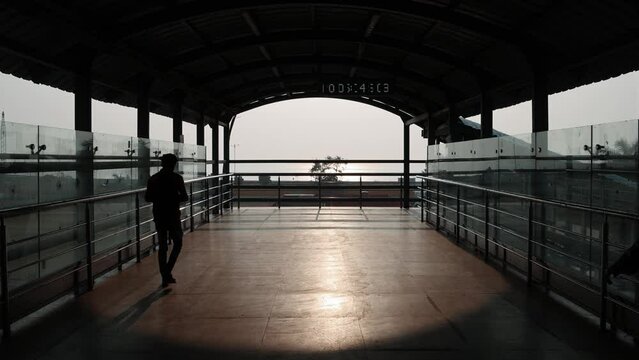 Silhouette shot of a Railway Foot over bridge on the western railway line facing the sun. People walking on the bridge during evening. Mumbai, Maharashtra, India. 4779.