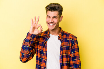 Young caucasian man isolated on yellow background cheerful and confident showing ok gesture.