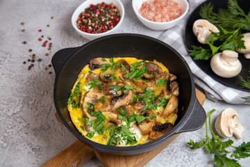 Frittata with champignons and herbs in a frying pan, top view.