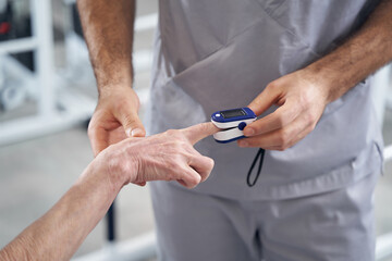 Medic using digital pulse oximeter on patient fingertip
