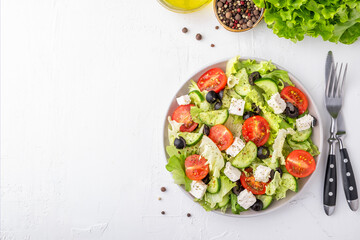 Cherry tomatoes, cucumber, lettuce and cheese on a plate. Healthy food concept. Top view, copy space