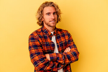 Young caucasian man isolated on yellow background who feels confident, crossing arms with...