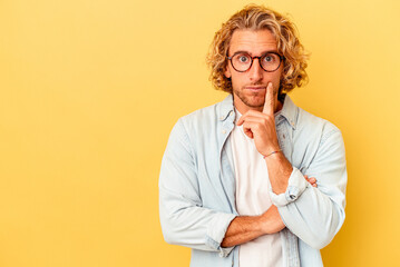 Young caucasian man isolated on yellow background looking sideways with doubtful and skeptical expression.