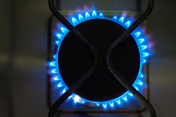 Close up of an old lit gas stove with blue flame
