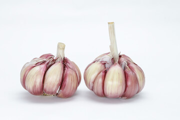 Two heads of garlic (Allium sativum) with its units still in the bulb and husk on a neutral background