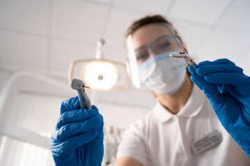 Dentist woman alone holding dental instruments, looking at the camera. Personal or patient point of view, POV. dental treatment concept.