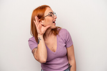 Young caucasian woman isolated on white background trying to listening a gossip.