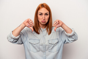 Young caucasian woman isolated on white background showing a dislike gesture, thumbs down....