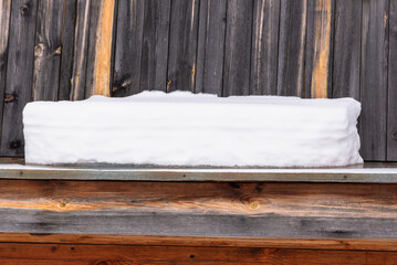 Snow lies on the small roof of a wooden house.