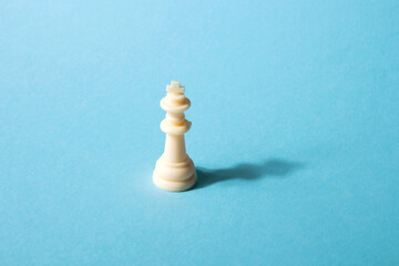 White chess queen on a blue background. Abstract background. Chess piece. Concept of leadership, loneliness