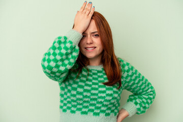 Young caucasian woman isolated on green background forgetting something, slapping forehead with palm and closing eyes.