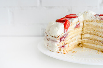 Delicious cake with cream cheese and strawberries. Beautiful serving on a white brick background