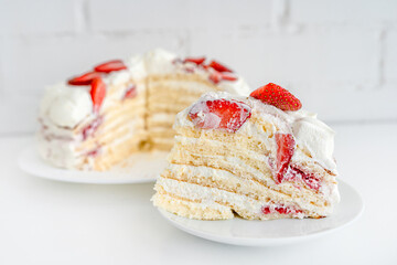 Delicious cake with cream cheese and strawberries. Beautiful serving on a white brick background