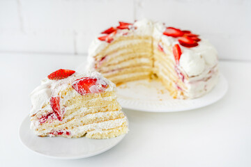 Delicious cake with cream cheese and strawberries. Beautiful serving on a white brick background