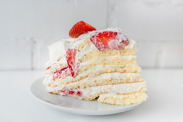 Delicious cake with cream cheese and strawberries. Beautiful serving on a white brick background