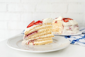 Delicious cake with cream cheese and strawberries. Beautiful serving on a white brick background