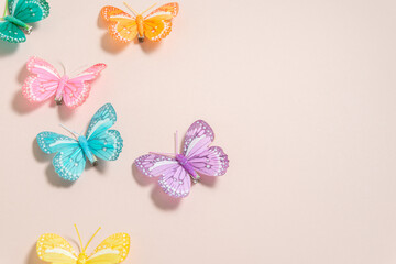 multicolored handmade butterflies on a pale pink background, free space for text, elegant spring composition