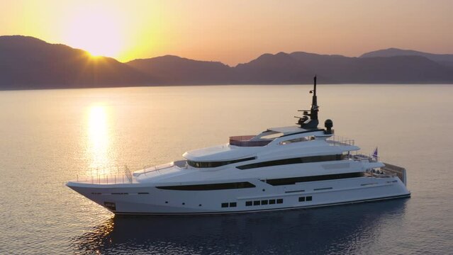 A superyacht moored in a calm sea at colorful sunset