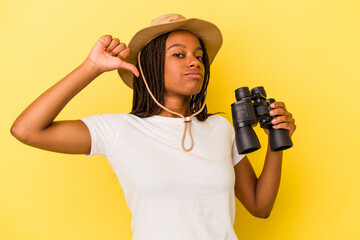 Young african american explorer woman holding a binoculars isolated on yellow background  feels proud and self confident, example to follow.