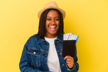 Young african american woman holding passport isolated on yellow background  laughing and having fun.