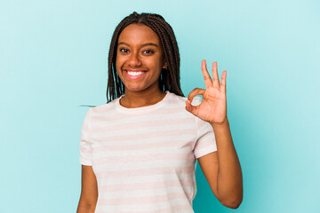 Young african american woman isolated on blue background  cheerful and confident showing ok gesture.