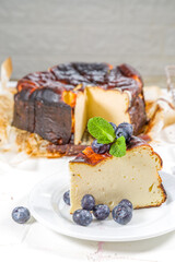 Homemade Burnt Basque Cheesecake,  Piece of Basque burnt cheesecake with berry decor and whole cake. Tarta de Queso Spanish recipe concept