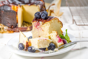 Homemade Burnt Basque Cheesecake,  Piece of Basque burnt cheesecake with berry decor and whole cake. Tarta de Queso Spanish recipe concept