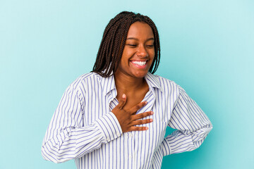 Obraz premium Young african american woman isolated on blue background laughing keeping hands on heart, concept of happiness.