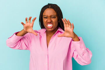 Young african american woman isolated on blue background  upset screaming with tense hands.