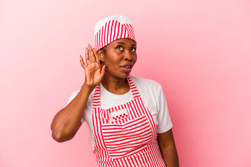 Young african american ice cream maker woman isolated on pink background trying to listening a gossip.