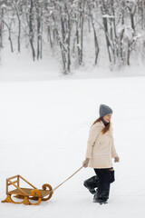 Young woman on a winter walk with a sled. Winter outdoor activities