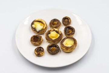 Baked mushrooms in a ceramic plate on a white background. Cultivated mushroom or portabello mushroom