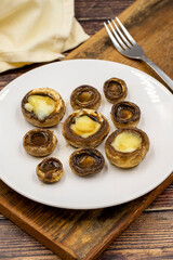 Baked mushrooms in a ceramic plate on a wooden background. Cultivated mushroom or portabello mushroom